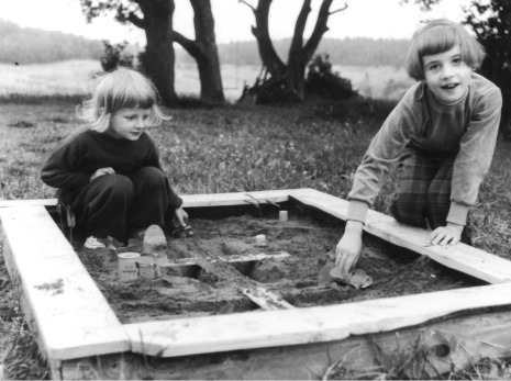 Flickor leker i sandbox.